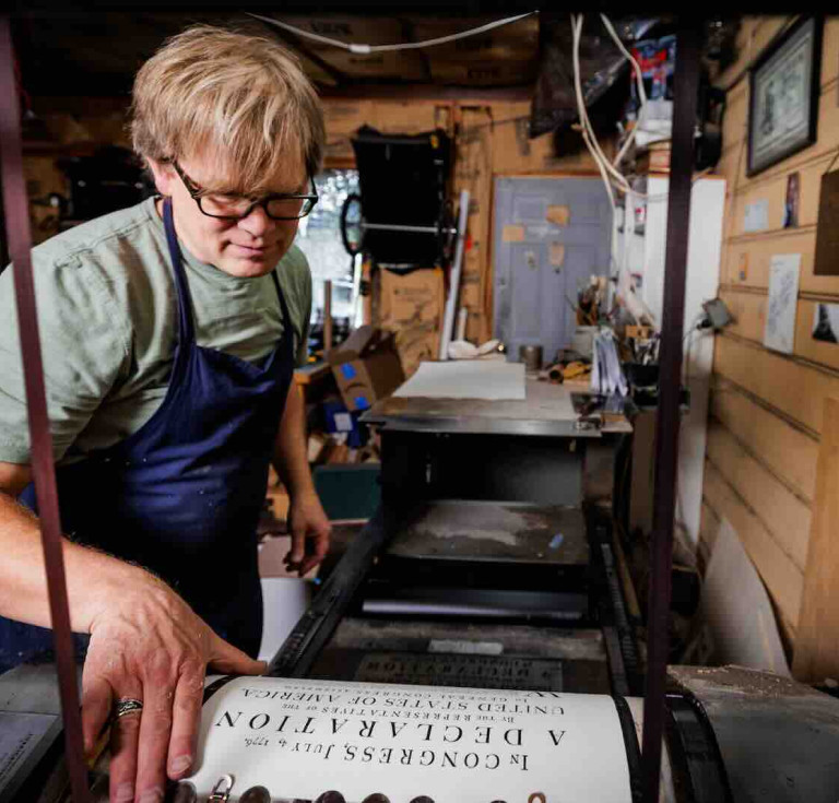 Utah artist Rob Buchert examines a freshly printed sheet of his recreation of the 1776 Declaration of Independence from the press. Every copy was printed one sheet at a time, by hand, on paper he made himself using 18th century methods